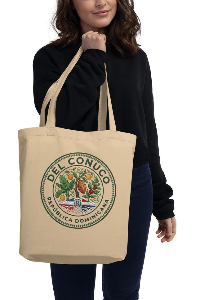 Natural organic cotton eco tote bag with Del Conuco Heritage Edition brand seal featuring cacao pod, banana leaves, coffee cherries, chinola vines, and Dominican flag at the base